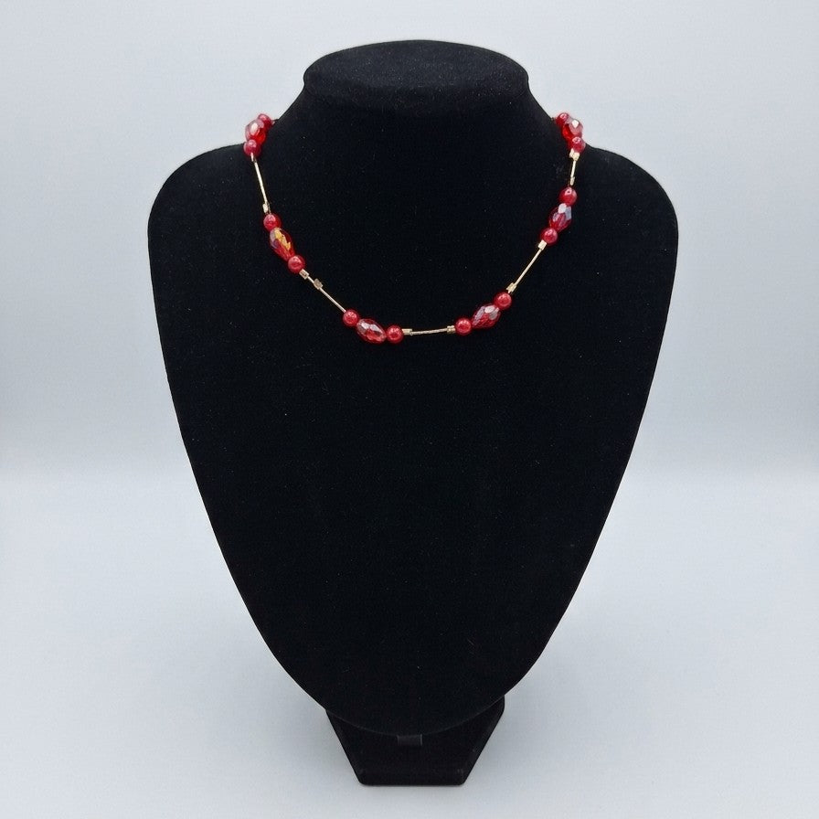 A red floating bead choker necklace on a black jewellery stand.