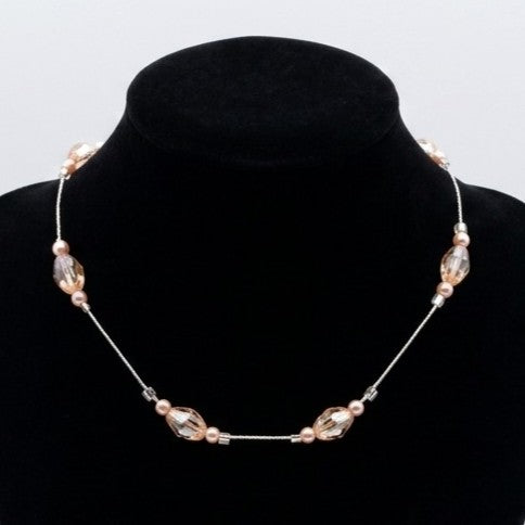 A delicate floating bead necklace with faceted and smooth glass beads, displayed on a black velvet jewellery bust.