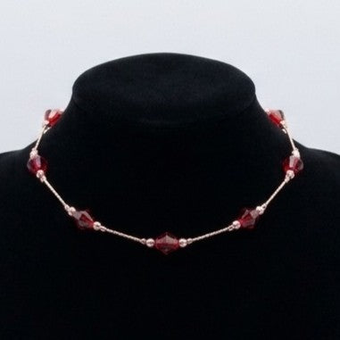 A delicate floating bead chain necklace, displayed on a black jewellery stand.