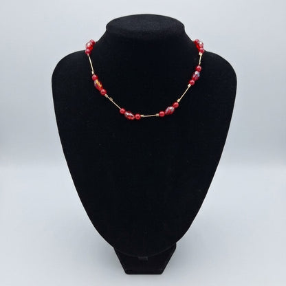 A red floating bead choker necklace on a black jewellery stand.
