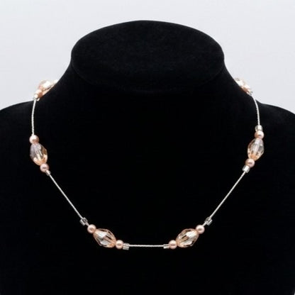 A delicate floating bead necklace with faceted and smooth glass beads, displayed on a black velvet jewellery bust.