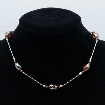 Floating bead choker necklace with smooth and faceted beads, displayed on a black jewellery stand.