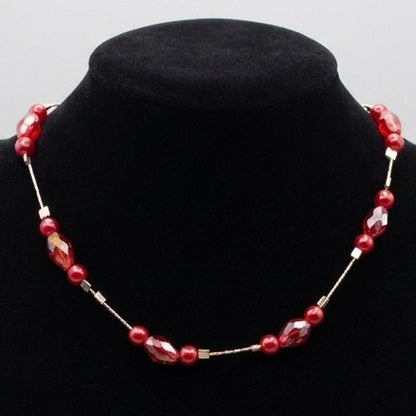 A red floating bead necklace with faceted crystal accents, displayed on a black velvet jewellery bust.